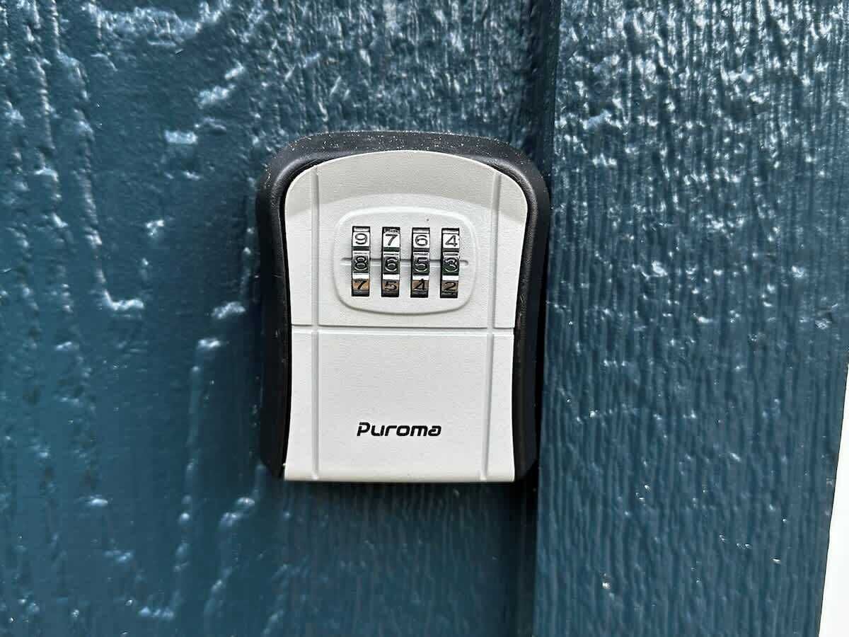 A white security keypad with the brand name 'Puroma' on a textured blue surface.