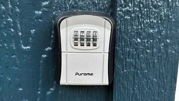 A white security keypad with the brand name 'Puroma' on a textured blue surface.