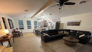 A spacious living room with a sectional sofa, a coffee table, and a dining area with chairs and a table. - Rio Verde - Cozy Cottage on the Frio River  (Leakey)
