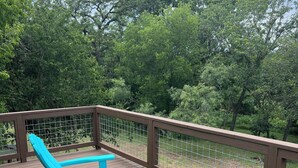 A wooden deck with turquoise Adirondack chairs and a metal fence. - Rio Verde - Cozy Cottage on the Frio River  (Leakey)