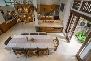 Una cucina moderna con isola centrale, zona pranzo con tavolo e sedie, e vista sull'esterno.