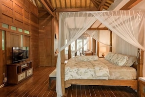 A wooden room with a bed, a TV, and a canopy bed. - The Lavana Ziza Living And Villas Seminyak (Bali)