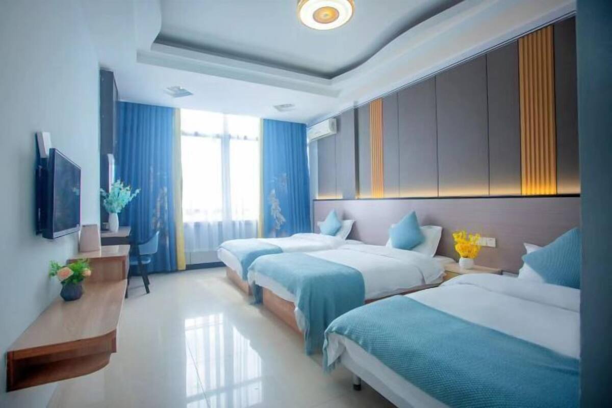 A modern hotel room with two beds, a desk, and a TV.