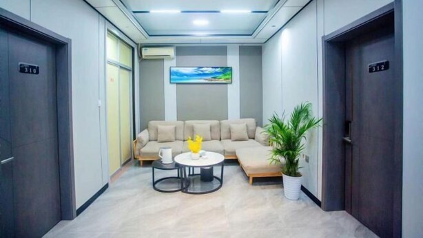 A modern lobby with a sofa, coffee table, and potted plant. - Chaoyang Hotel (Putian)