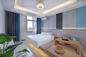 A modern hotel room with a bed, bedside table, and a view of the city. - Chaoyang Hotel (Putian)