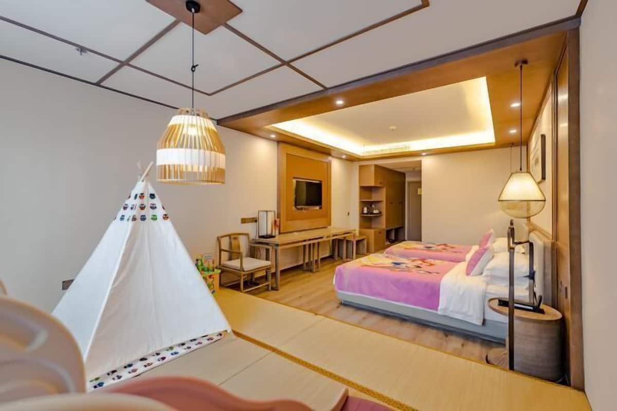 A hotel room with a bed, a desk, a chair, a tent-like structure, and a television.