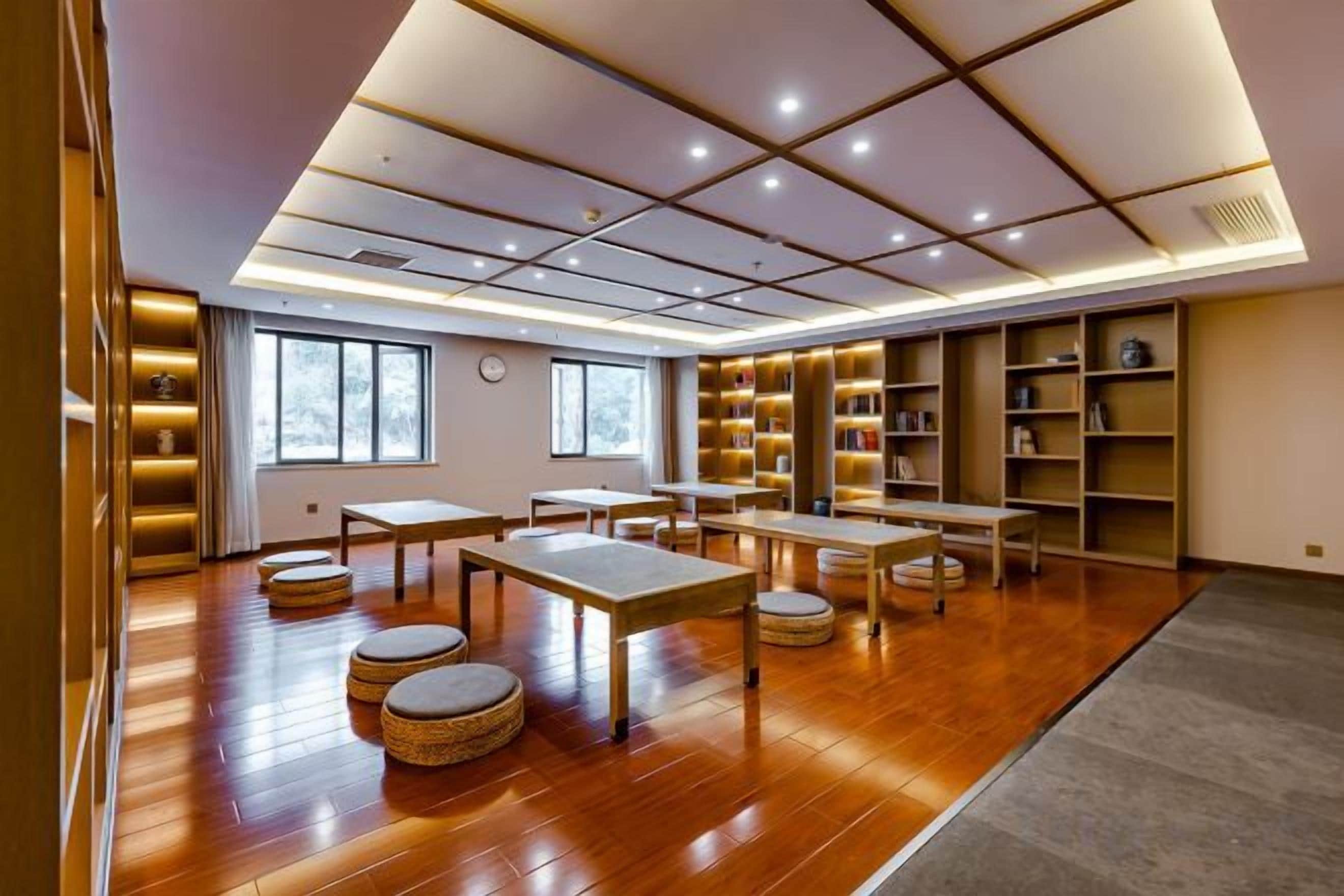 A spacious room with wooden flooring, tables, and chairs, and bookshelves along the walls.
