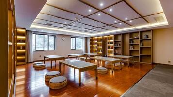 A spacious room with wooden flooring, tables, and chairs, and bookshelves along the walls.