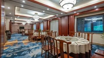 Un comedor de hotel con varias mesas redondas, sillas y candelabros.