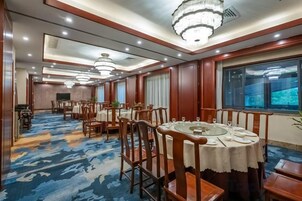 Un comedor de hotel con varias mesas redondas, sillas y candelabros.