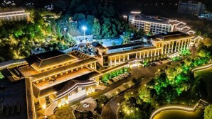 An aerial view of a hotel with multiple buildings, a parking area, and surrounding greenery. - Tangtaizong Hot Spring Resort (Lushan City)