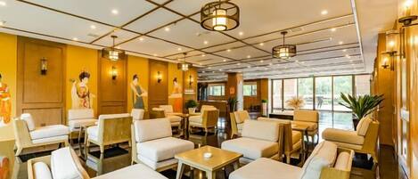 A hotel lobby with seating areas, tables, and a reception desk.