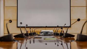 A conference room with a whiteboard, a projector, and multiple microphones on a table.