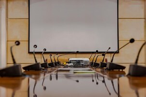 A conference room with a whiteboard, a projector, and multiple microphones on a table.