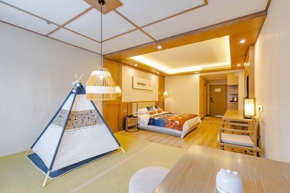 A hotel room with a bed, bedside table, lamp, and a unique tent-like decoration.