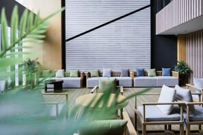 A modern lounge area with a sofa set, wooden furniture, and potted plants. - Tangtaizong Hot Spring Resort (Lushan City)