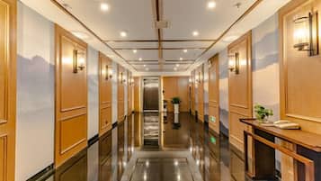 Un pasillo de hotel con paneles de madera, un mostrador de recepción y una escalera que sube a otro piso.