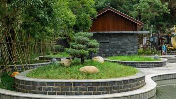 A traditional building surrounded by a landscaped garden with stone pathways and neatly trimmed bushes.