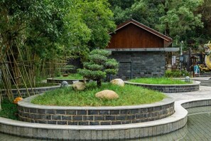 Un bâtiment traditionnel entouré d’un jardin aménagé, avec des allées pavées et des arbustes soigneusement taillés.