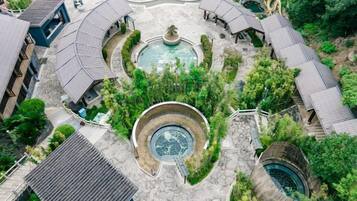 Vista aerea di un cortile con una fontana centrale, circondato da edifici dalle curve coperture e una piscina.