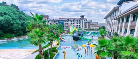 Un complejo turístico con piscina, palmeras y un edificio de varios pisos.
