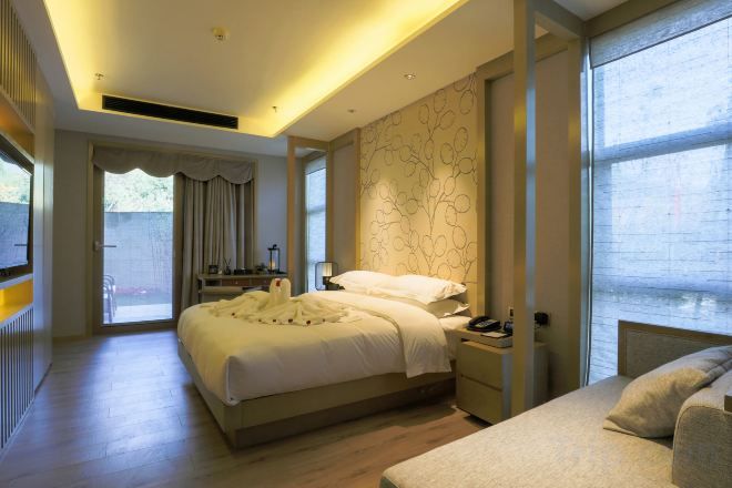 A modern bedroom with a large bed, bedside tables, and a view of the outdoors.