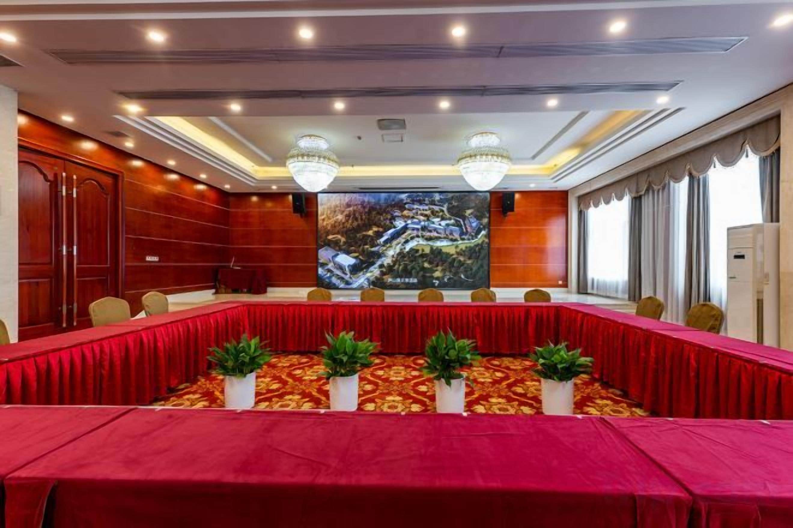 A conference room with a long table, chairs, and a large screen.