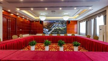 A conference room with a long table, chairs, and a large screen.