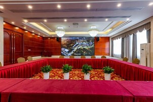 Un salón de conferencias con una mesa larga, sillas y una pantalla grande.