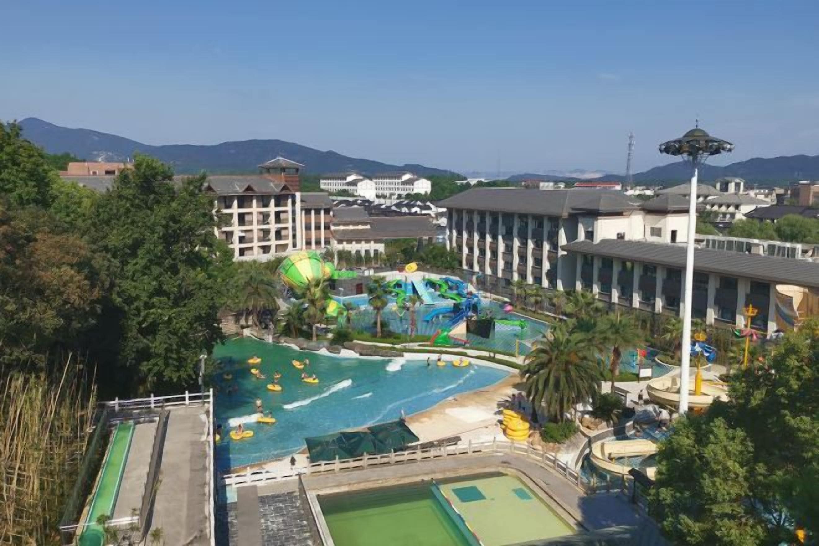 A resort with a swimming pool, water slides, and a view of mountains.