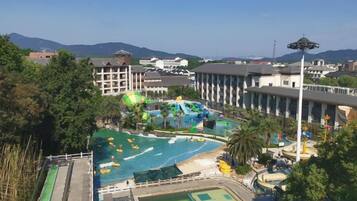 A resort with a swimming pool, water slides, and a view of mountains.
