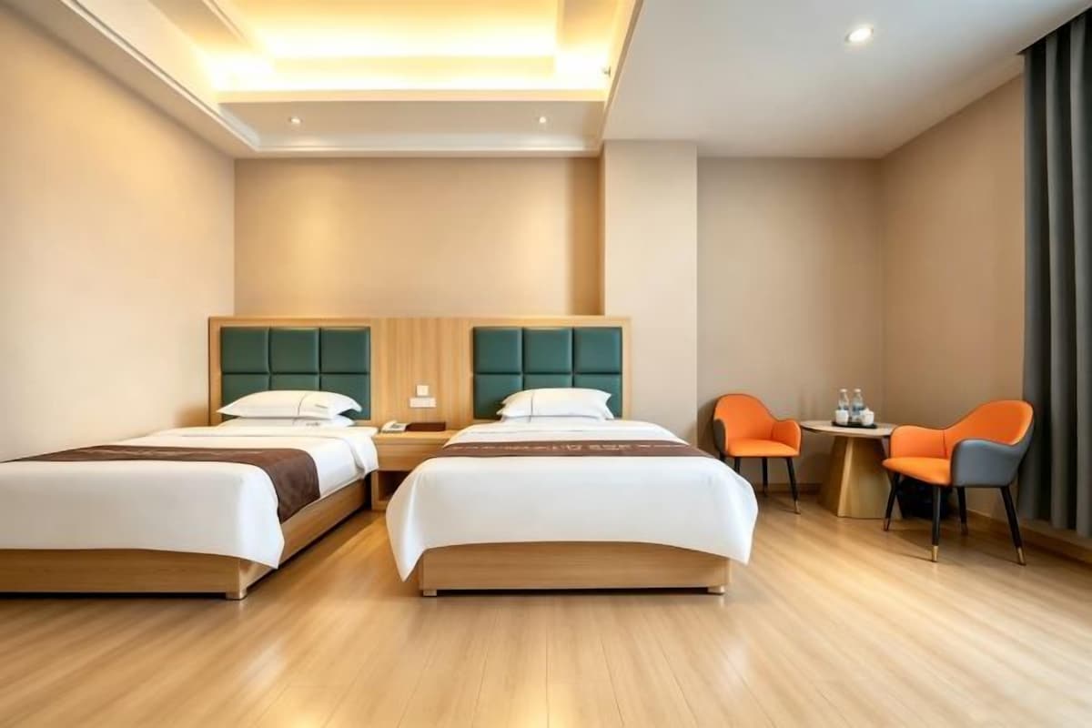A hotel room with two beds, a small table, and two chairs.