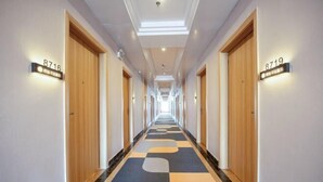 A hotel corridor with wooden doors, numbered signs, and a patterned carpet. - Rongyue Hotel (Yangjiang)