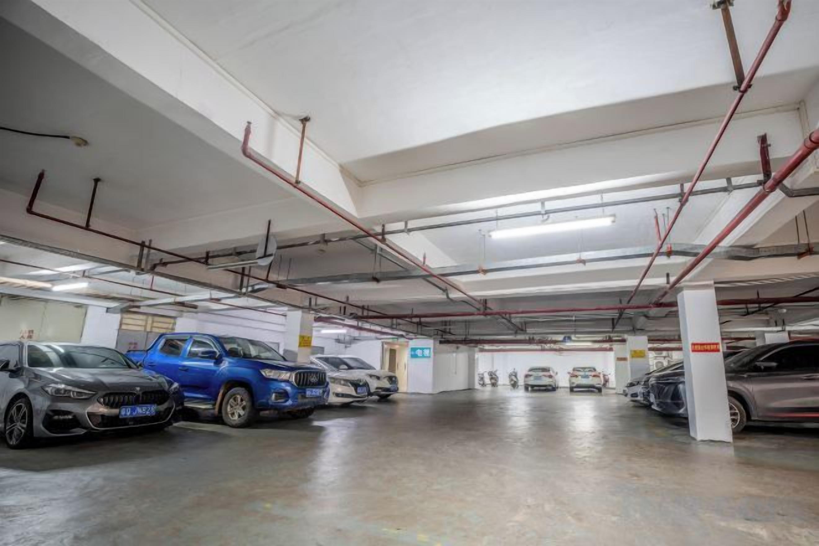 Un garaje de varios niveles con varios coches estacionados, vigas estructurales visibles y un interior blanco e impecable.