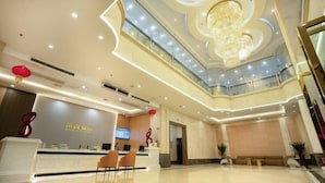 A hotel lobby with a reception desk, seating area, and a chandelier. - Rongyue Hotel (Yangjiang)