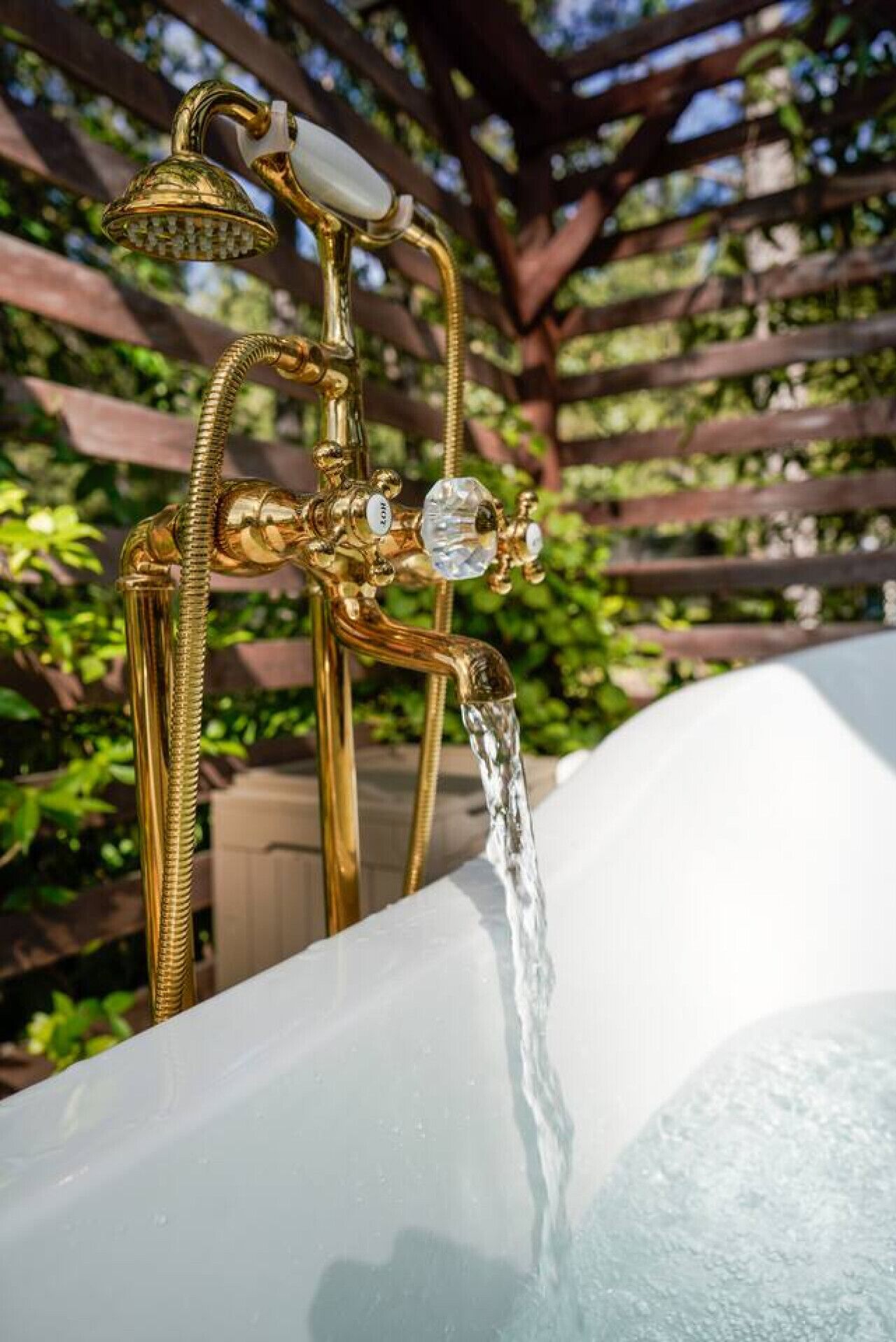 A gold-colored outdoor hot tub with a showerhead and a faucet.