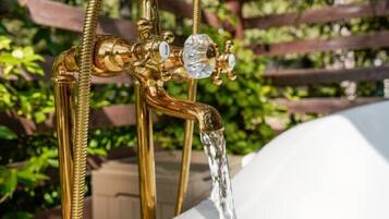 A gold-colored outdoor hot tub with a showerhead and a faucet.