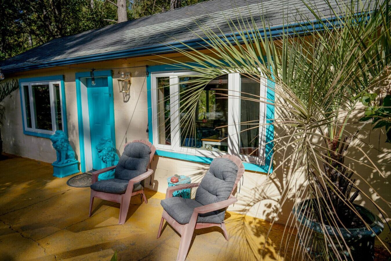 Una piccola casa con due sedie e un tavolo all'esterno, immersa nel verde.