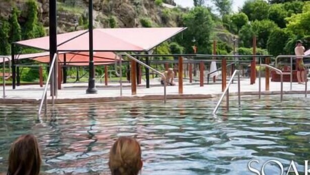 Una piscina con zona de sombra y vistas a un promontorio rocoso.