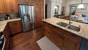 Una cocina moderna con armarios de madera, electrodomésticos de acero inoxidable, encimeras de granito y un lavamanos integrado.