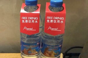 Two bottles of water with red and blue labels, one with English and Chinese text, and the other with Chinese text only. - Jinhua Lianyi Hotel (Jinhua)