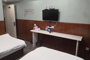 Camera d'albergo con due letti, una TV fissata al muro, una scrivania e articoli da toilette, e una porta.