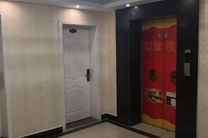 Un pasillo con una puerta blanca y una puerta de ascensor roja con caracteres chinos.