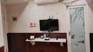A room with a mounted television, a small shelf with items, a door with a decorative panel, and an air conditioning unit. - Jinhua Lianyi Hotel (Jinhua)