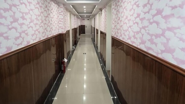 A long, narrow hallway with patterned wallpaper, wooden paneling, and a shiny tiled floor. - Jinhua Lianyi Hotel (Jinhua)