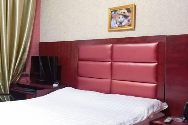 A hotel room with a bed, a television on a stand, a framed picture on the wall, and a curtain. - Jinhua Lianyi Hotel (Jinhua)