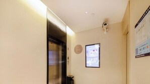 A hallway with a closed elevator, a trash bin, and a digital information board on the wall. - Home Inn Neo Shenzhen East Railway Station Changlong Metro Station (Shenzhen)