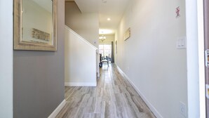 A hallway with a wooden floor, a framed picture on the left, and a door on the right.
