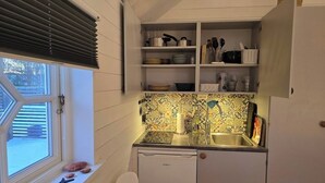 A compact kitchen with a window, a dishwasher, and shelves with kitchenware. - Charming 2-bedroom house new built in wonderful Grebbestad  (Grebbestad)
