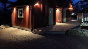 A wooden cabin with a porch and a small deck, surrounded by trees. - Charming 2-bedroom house new built in wonderful Grebbestad  (Grebbestad)